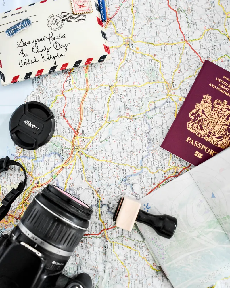 A road map spread out on a table with a passport, a camera and an airmail envelope