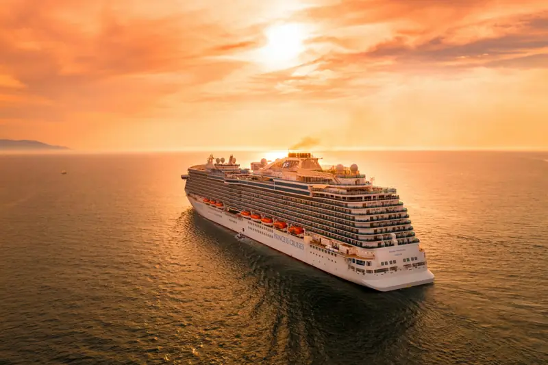 A white cruise ship sailing on a calm sea at sunset