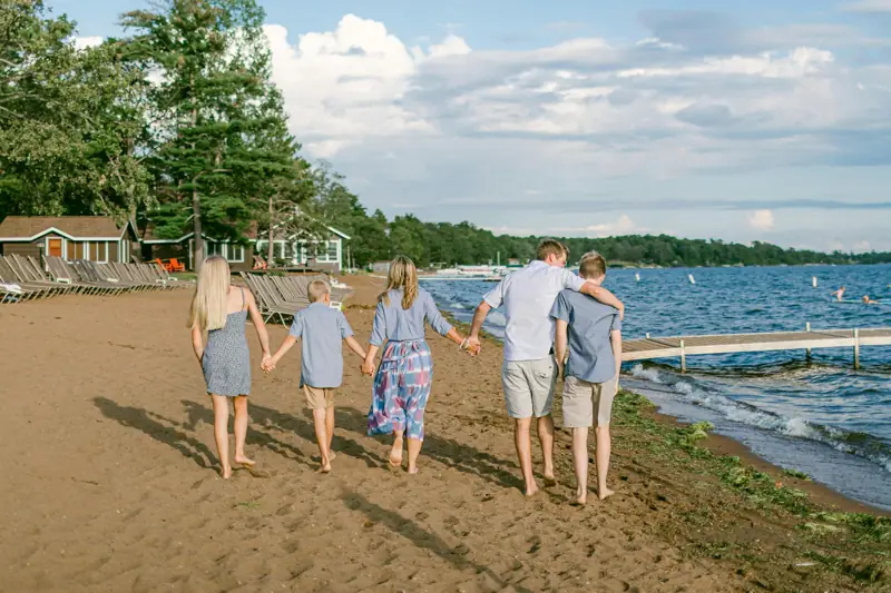 A family seen from behind, walking hand in hand along a sandy beach