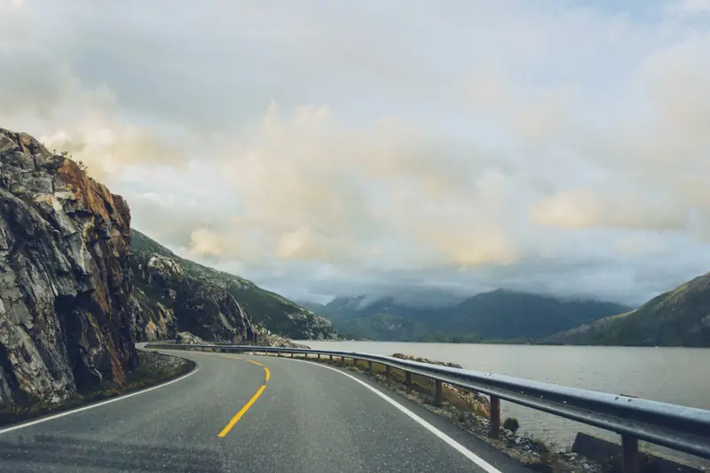 A winding coastal road between mountains and the sea